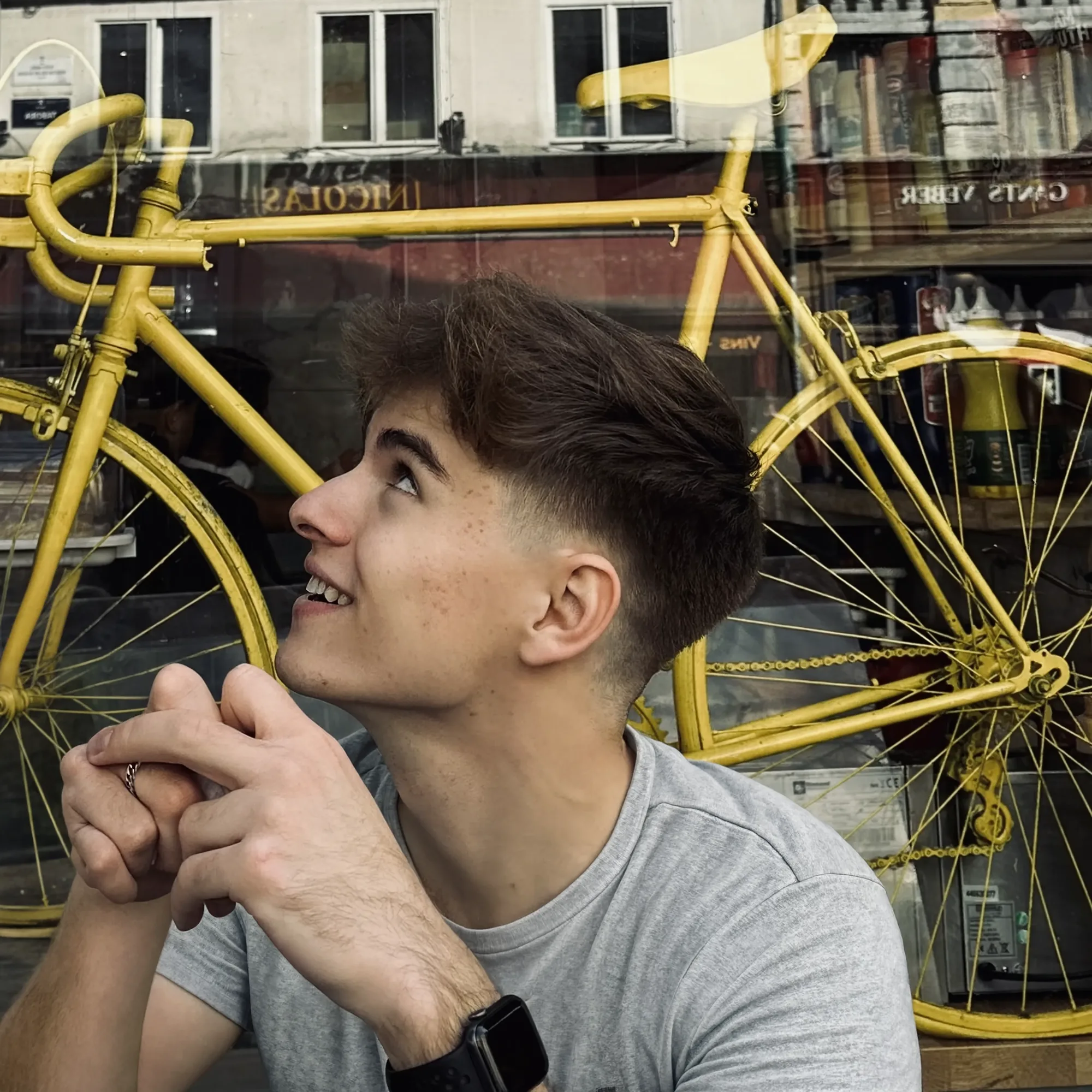 Emmett Hintz looking upward beside a yellow bicycle in a shop window